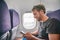 Plane passenger man texting on mobile phone using in-flight onboard wifi internet on business travel trip holding