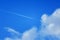 Plane with white footprint in the blue sky with clouds_