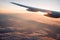 Plane wing above the clouds in the sunrise, sunglight rays visible through the plane wing