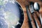 The planet Earth plate with a fork and knife on a wooden background. World hunger concept. Feed the world