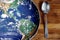 The planet Earth plate with a fork and knife on a wooden background. World hunger concept. Feed the world