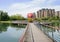 Plank-paved footbridge over lake in modern city of sunny summer