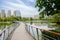 Plank-paved footbridge over lake in modern city at sunny summer