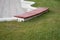 Plank seating on high white stone curb and mowed lawn  background