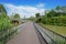 Planked steel footbridge over river in sunny summer afternoon