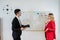 Planning business together - man and woman discussion new business idea near whiteboard in office
