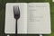 Plant-based diet green notebook with food category list on tropical leaf with fork and plants