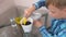 Plant care concept. Boy is planting houseplant. Shifts the earth in a pot with a small showel.