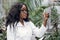 Plant protection concept, botany research. Close up of beautiful African woman biologist in white coat, holding test