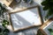 Plantfilled rectangular frame on wooden table with leaves