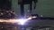 The plasma cutter in operation cuts with sparks a thick metal sheet into small parts at the factory