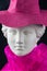 Plaster copy of ancient statue head in pink hat and scarf on a black background. Gypsum sculpture female face.