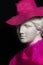 Plaster copy of ancient statue head in pink hat and scarf on a black background. Gypsum sculpture female face.