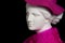 Plaster copy of ancient statue head in pink hat and scarf on a black background. Gypsum sculpture female face.