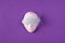 Plaster face, eyes covered with gentle blue feather against violet background. Minimalist Woman theme concept.