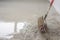 plasterer during floor covering works with self-levelling cement mortar, uses a needle roller