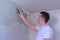 Plasterer man spackling wall with putty plaster aligning wall using trowel.