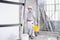 Plasterer man work holds a bucket front the wall of interior construction site wear helmet and protective gloves, ladder and