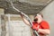 Plasterer spraying plastering mortar on ceiling with sprayer machine