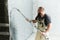 Plasterer using screeder spraying putty plaster mortar on wall