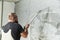 Plasterer using screeder spraying putty plaster mortar on wall