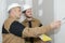 Plasterer worker with spatula pointing at wall