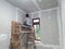 Plasterwork and wall painting preparation. Asian male applying plaster or filling drywall patch