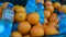 Plastic baskets with ripe oranges on the ground and sellers, bottles with water and scales near them on the street market in