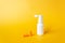 Plastic blank ear spray bottle with nozzle and orange earplugs isolated on yellow background. For daily ears hygiene.