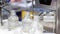 Plastic bottles are filled with clear liquid on a conveyor belt at a factory