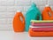 Plastic bottles with liquid detergent and folded towels on a white shelf. Bath interior