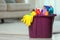 Plastic bucket with different cleaning products on floor indoors