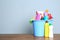 Plastic bucket with different cleaning products on table against color background