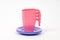 Plastic children`s pink mugs and lilac plates on a white background