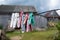 Plastic clothespins hang on clotheslines, in a rustic courtyard, against the backdrop of a wooden barn and the sky.