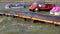 Plastic colorful boats in shape of cars on sea water waves and wooden pier