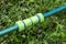 the plastic connector for the watering hose lies on the green grass