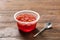 Plastic container with tasty jelly and spoon on table