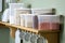 Plastic containers filled with cereals buckwheat, oatmeal, lentils, flour are on a shelf in the kitchen.