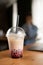 Plastic cup of fresh bubble drinks on wooden table in cafe over male client background