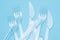 Plastic disposable tableware, cutlery. Fast food. Clean plastic forks and knives on blue background. Disposable dishes,