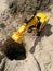 Plastic excavator child toy digging holes on the beach