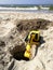 Plastic excavator child toy digging holes on the beach