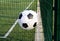 Plastic garbage can in the shape of a soccer ball near fenced football ground