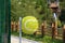 Plastic garbage can in the shape of a tennis ball on the path in the suburban park