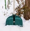 Plastic green shovel sticking out of a pile of snow