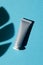 Plastic grey tube for cream or lotion. Skin care or sunscreen cosmetic in top view on blue background