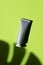 Plastic grey tube for cream or lotion. Skin care or sunscreen cosmetic in top view on green background