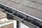 Plastic guard brush in new dark grey plastic rain gutter on asphalt shingles roof.