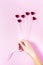 Plastic hearts on a pink background as a cluster of ballon, holding by a woman`s hand.